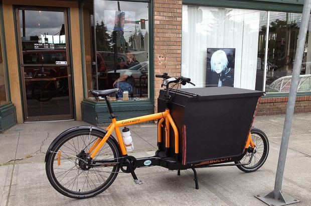 A cargo bike parked on a street outside a row of shops (Creative Commons Licence)
