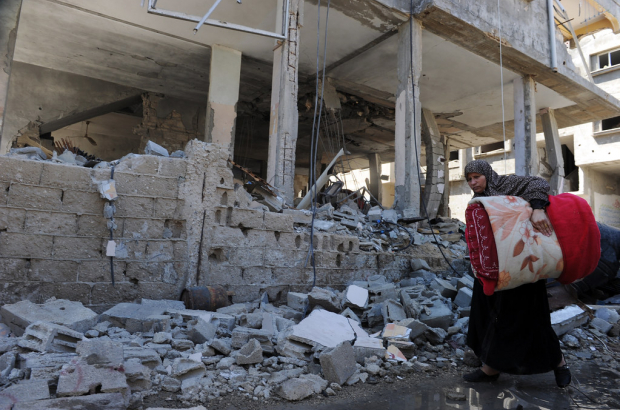 A Palestinian woman walks past a building destroyed by an Israeli air strike in Gaza City (Photo: Wikipedia Creative Commons / No Licence)
