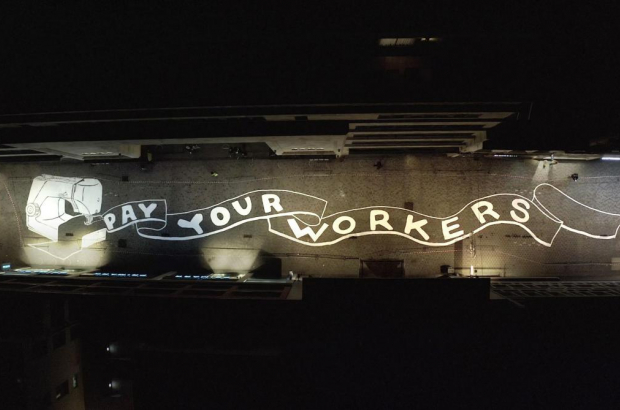 The slogan "Pay Your Workers" is seen painted on the street of Rue Neuve, Brussels (achACT)