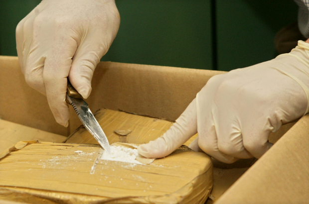 A police officer scoops a specimen of cocaine from a package discovered in Gent. Belgium has seen a significant rise in cocaine entering the country over the past year. (BELGA PHOTO LIEVEN VAN ASSCHE)