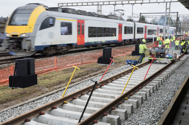 A GEN trains passes workers putting finishing touches to a new train line (BELA PHOTO)