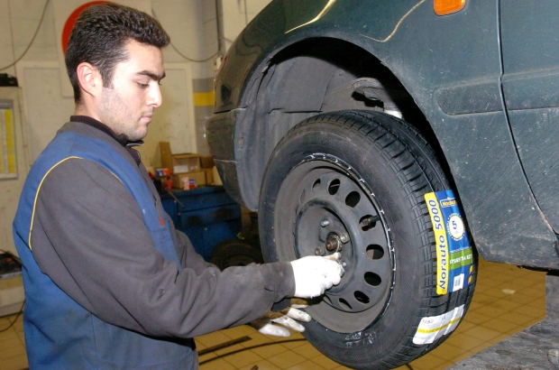 BRUSSELS, BELGIUM: Worker in a tyre specialist shop, replacing a tyre on a car. (BELGA PHOTO HERWIG VERGULT)