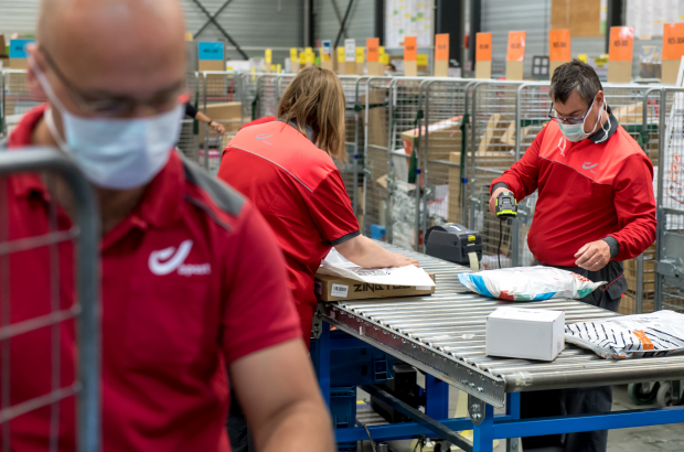 Illustration picture shows postal workers at a distribution centre of Belgian postal service Bpost in Braine l'Alleud. Post services notice a large rise in the distribution of packages, as more people order things online due to the strict corona-crisis security measures. BELGA PHOTO POOL DANNY GYS