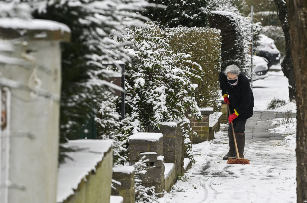 Illustration shows a person sweeping the snow, Monday 08 February 2021, in Brussels. Snow fall and cold temperatures are forecast for the rest of the day. The Royal Meteorological Institute KMI-IRM has issued a Code Yellow warning for slippery conditions. (BELGA PHOTO LAURIE DIEFFEMBACQ)