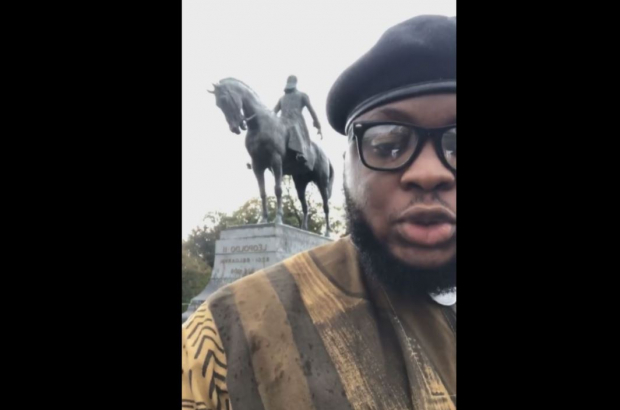 Egountchi Behanzin, the leader of the Black African Defence League (LDNA) , appears in the 15-minute-long video filmed at the base of the statue of Leopold II in Place de Trône, Brussels (© LDNA/Facebook)