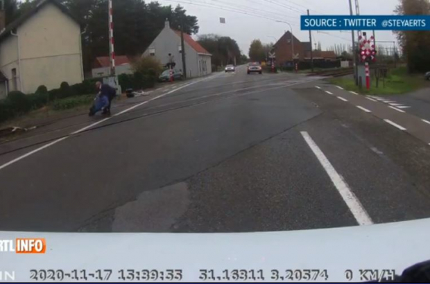 A screengrab from the dashcam video shows the bus driver pulling the cyclist from the train tracks at Loppem, Flanders, Nov. 25, 2020 (PHOTO ©RTL /Twitter @STEYAERTS