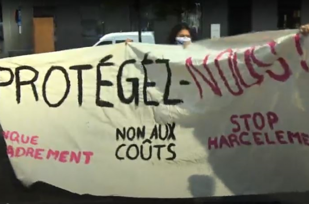 Students hold up a banner reading "Protect Us!" at the protest for legal protection for interns, Brussels, Oct 11 (RTBF, screenshot)
