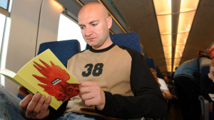 A man reads the book "het Vuur" by Bart Koubaa in the Oostende-Brussels train. (BELGA PHOTO LIEVEN VAN ASSCHE)