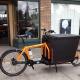 A cargo bike parked on a street outside a row of shops (Creative Commons Licence)